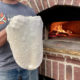 Pizza dough being stretched by oven